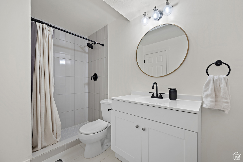 Full bath featuring vanity, a tile shower, and tile patterned flooring