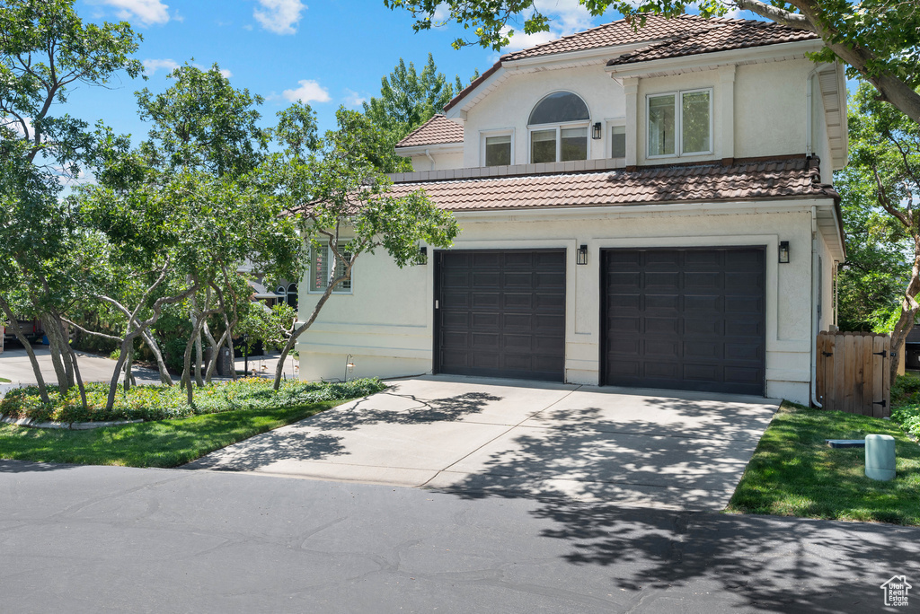 Mediterranean / spanish house with driveway, a tiled roof, a garage, and stucco siding