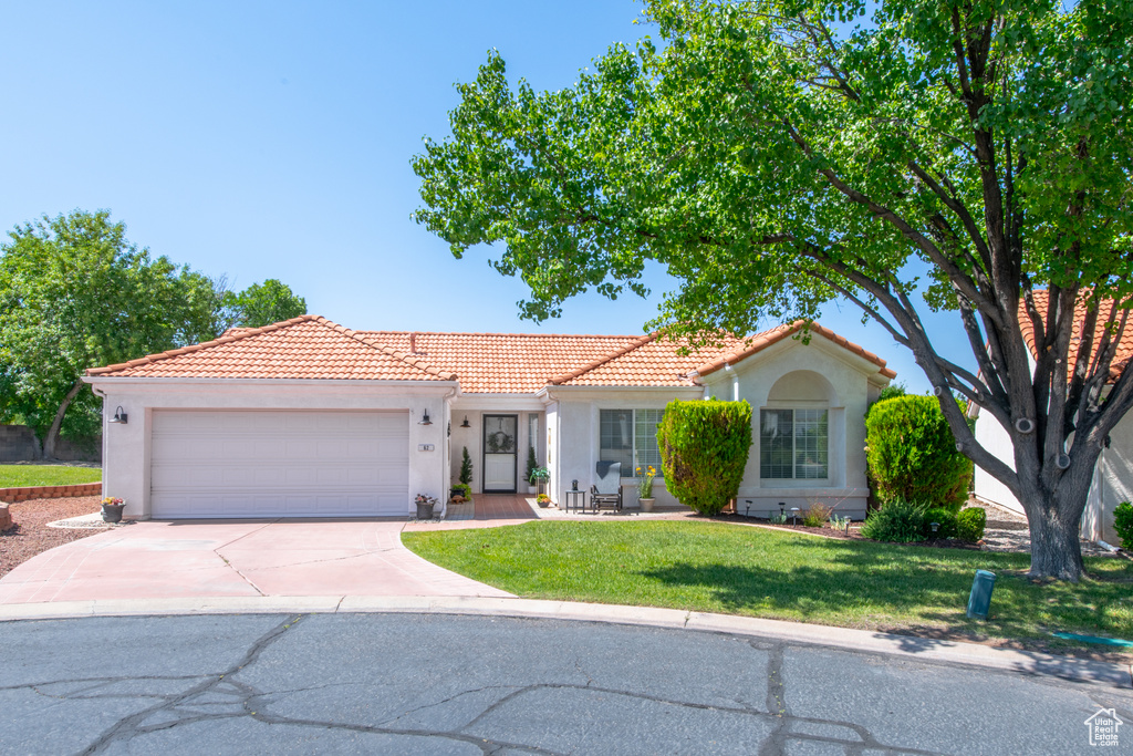 Mediterranean / spanish home with a tiled roof, a garage, concrete driveway, and stucco siding