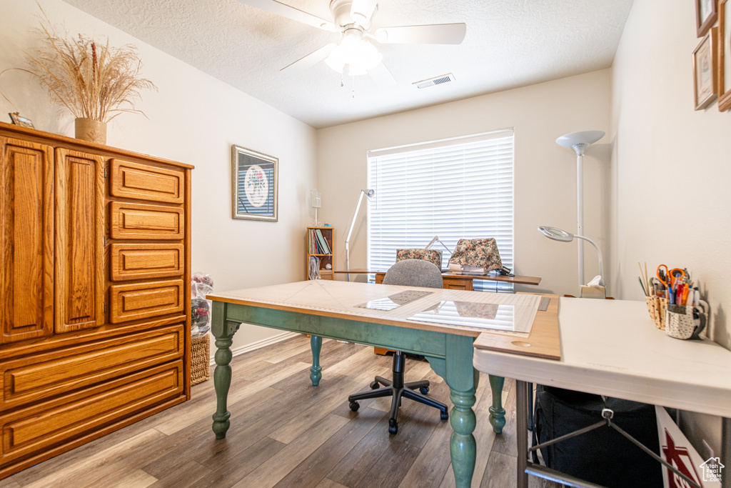 Home office featuring wood finished floors, ceiling fan, and a textured ceiling