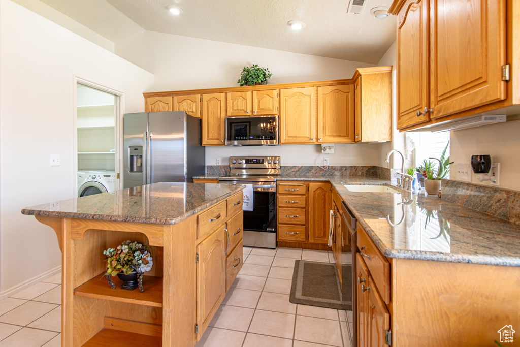 Kitchen featuring stainless steel appliances, open shelves, lofted ceiling, light tile patterned floors, and dark stone counters