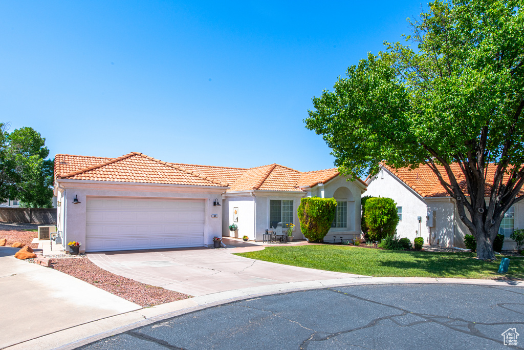 Mediterranean / spanish home with a tile roof, stucco siding, driveway, and a front yard