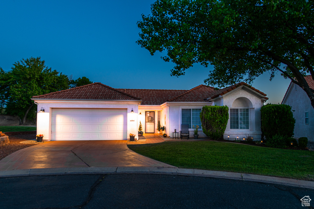 View of front of property featuring a tiled roof, concrete driveway, stucco siding, and an attached garage