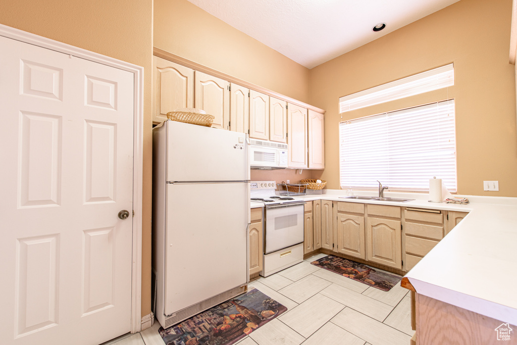 Kitchen featuring white appliances, light countertops, and light brown cabinetry