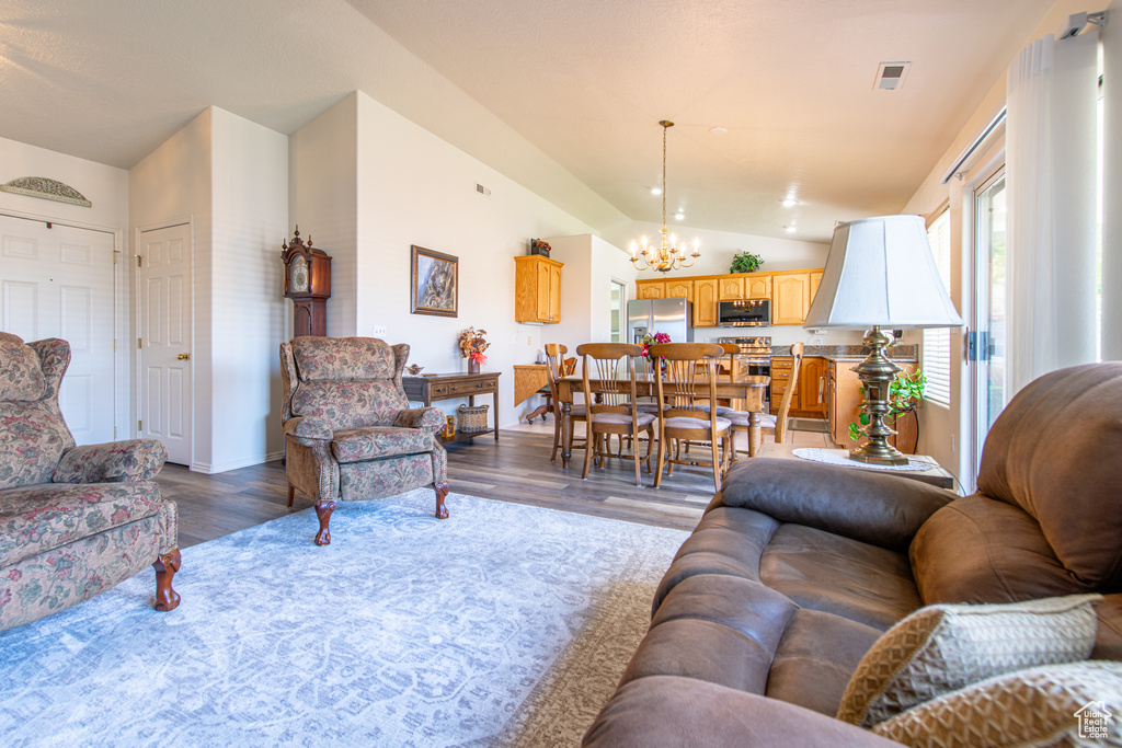 Living room with lofted ceiling, a chandelier, and wood finished floors