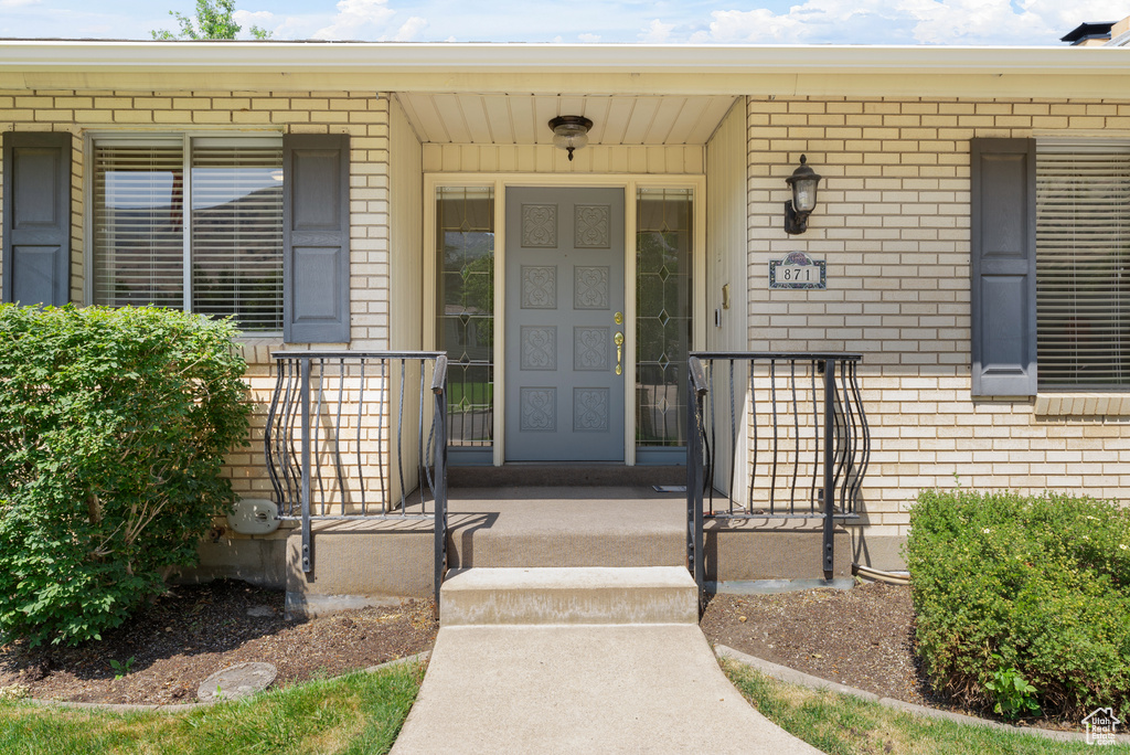 View of exterior entry featuring brick siding and a porch