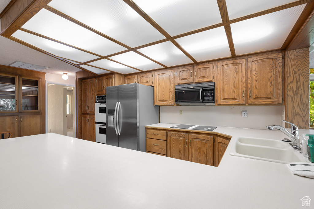 Kitchen featuring black appliances, light countertops, and brown cabinetry