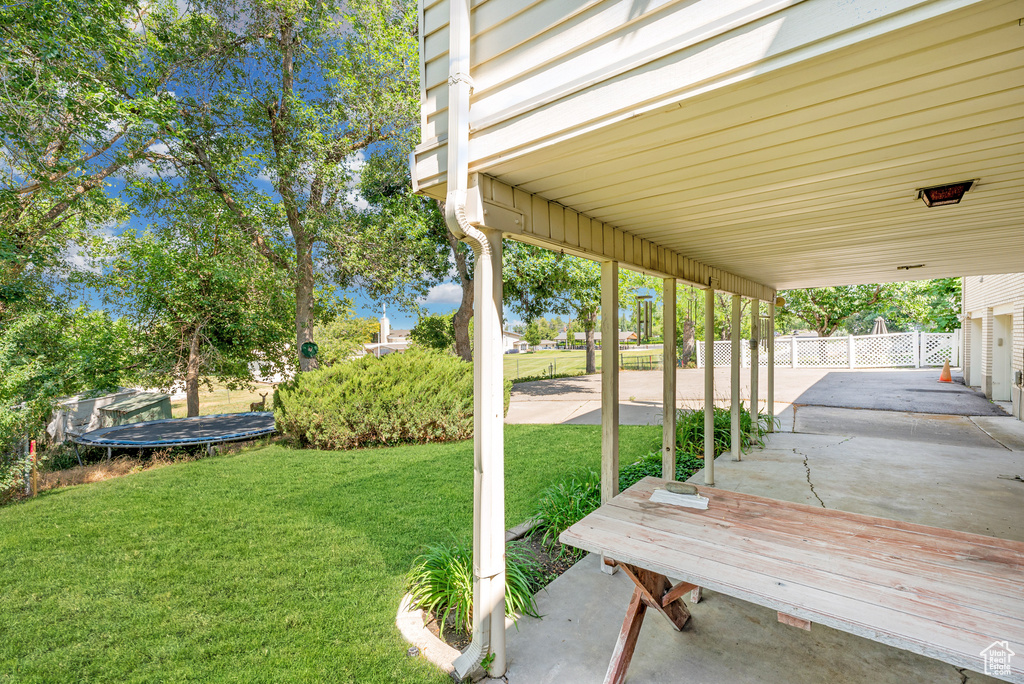View of yard featuring a trampoline and a patio