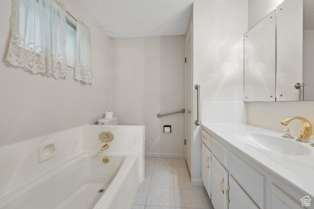 Bathroom featuring vanity, a bath, tile patterned flooring, and a textured ceiling