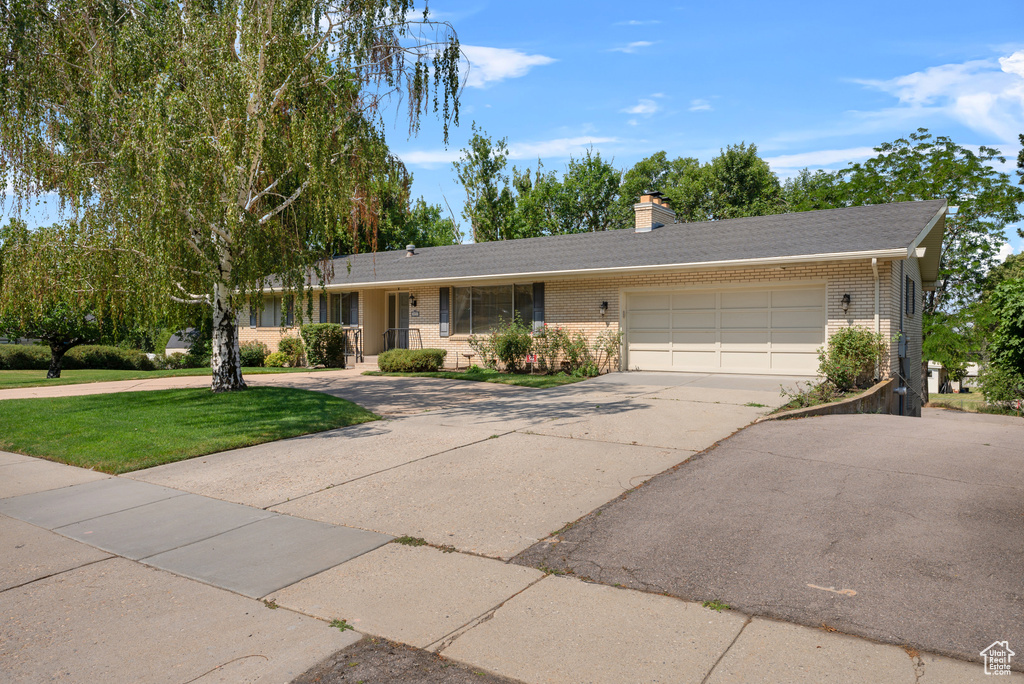 Ranch-style house featuring brick siding, driveway, a front yard, and a garage