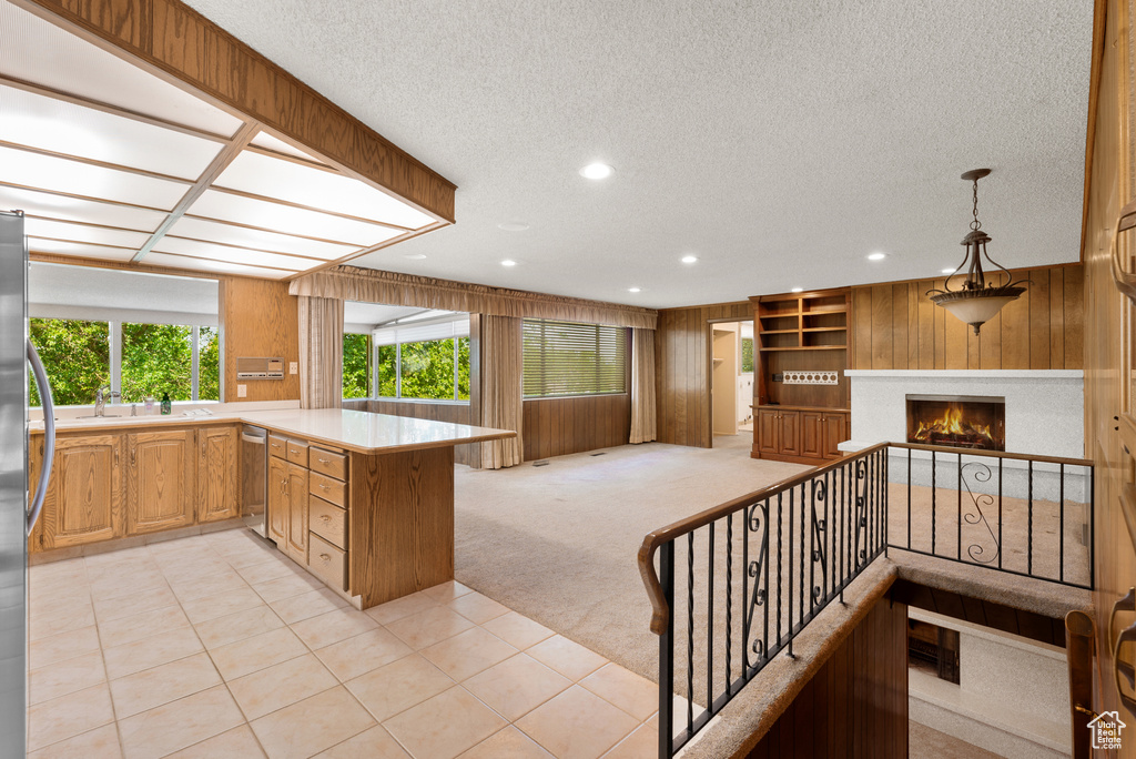 Kitchen with open floor plan, a textured ceiling, light countertops, a peninsula, and built in shelves