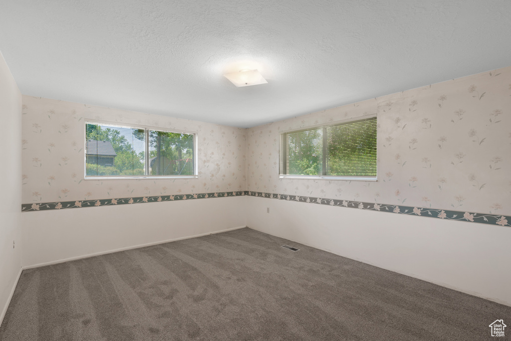 Spare room featuring wallpapered walls, carpet flooring, and a textured ceiling