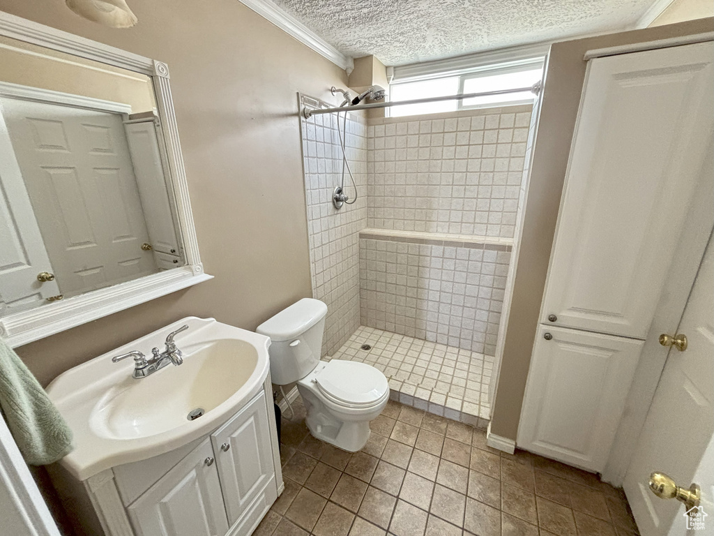 Bathroom featuring a stall shower, vanity, crown molding, and tile patterned flooring