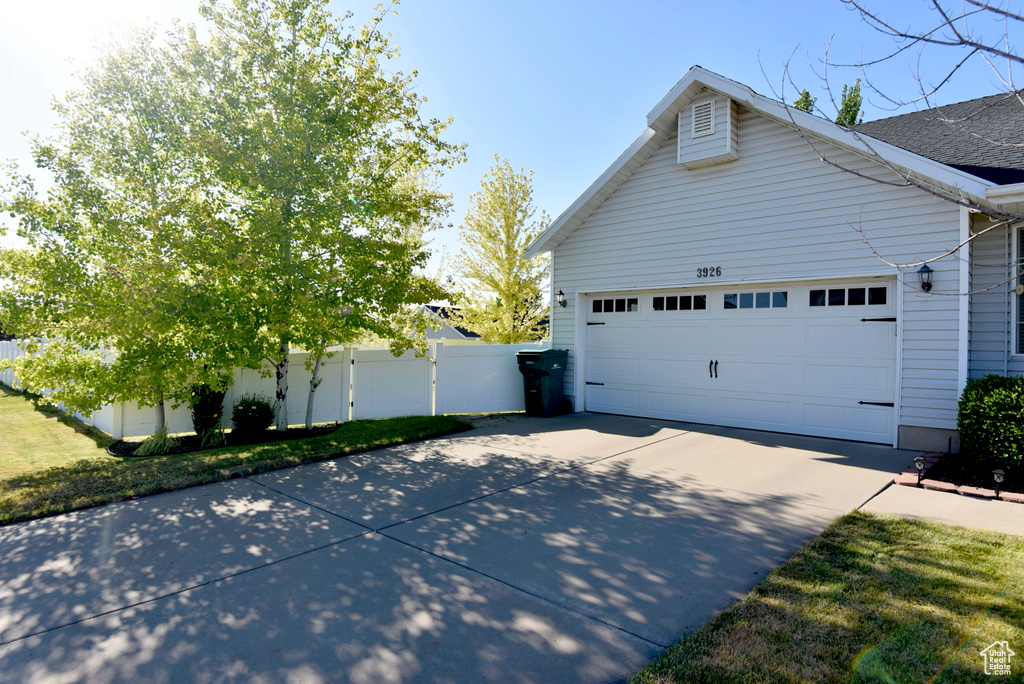 View of property exterior featuring concrete driveway and an attached garage