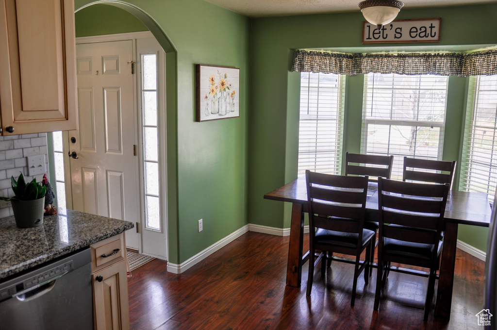 Dining room featuring dark wood-style flooring, healthy amount of natural light, and arched walkways