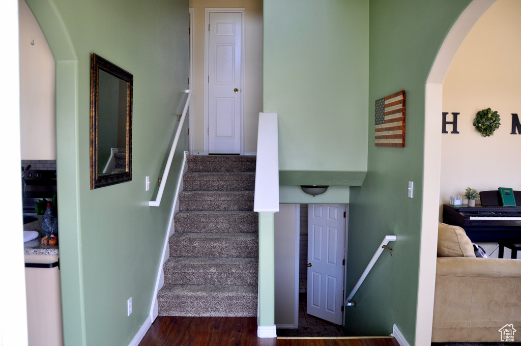 Staircase featuring arched walkways and wood finished floors