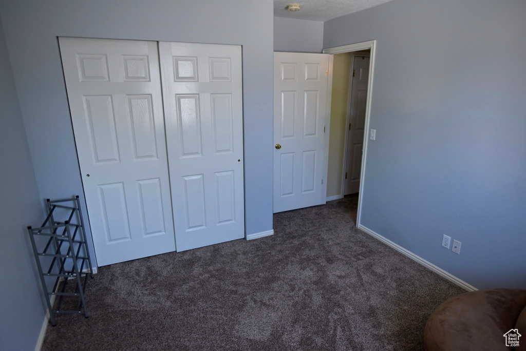 Unfurnished bedroom featuring dark carpet and a closet