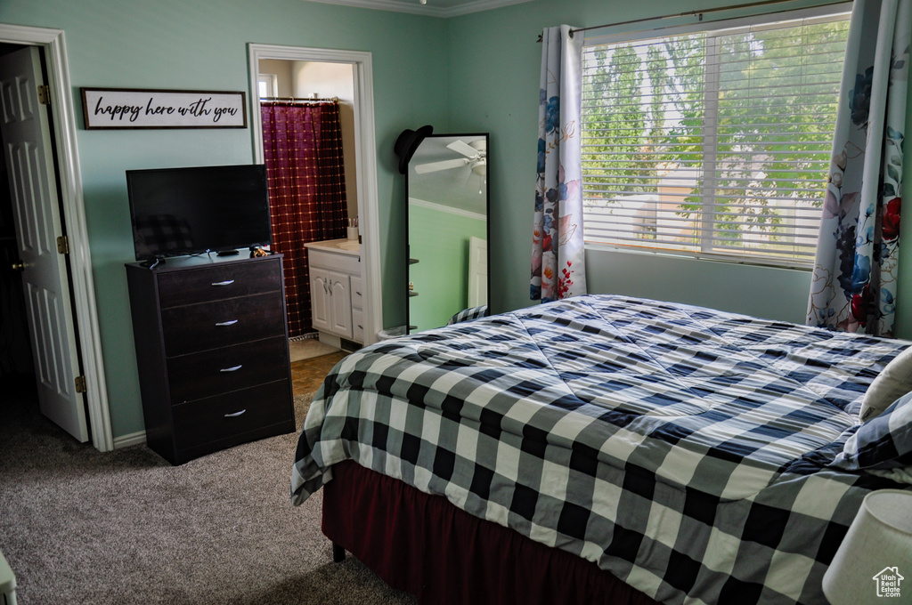 Carpeted bedroom with ensuite bath and ornamental molding