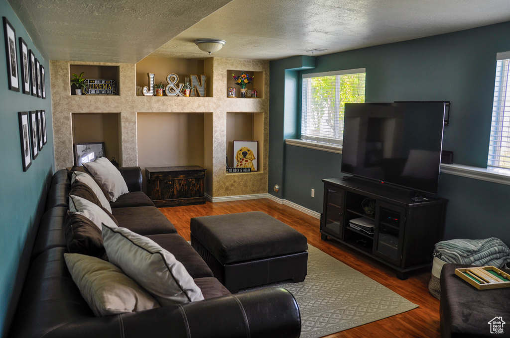 Living room with a textured ceiling, healthy amount of natural light, and wood finished floors