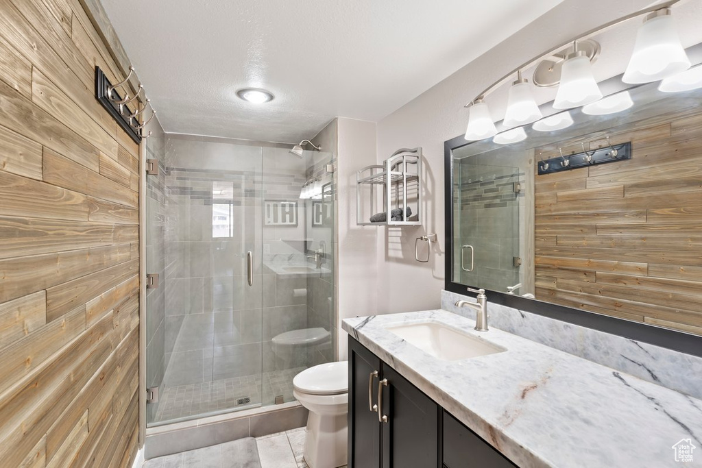 Full bath with vanity, a stall shower, and wood walls