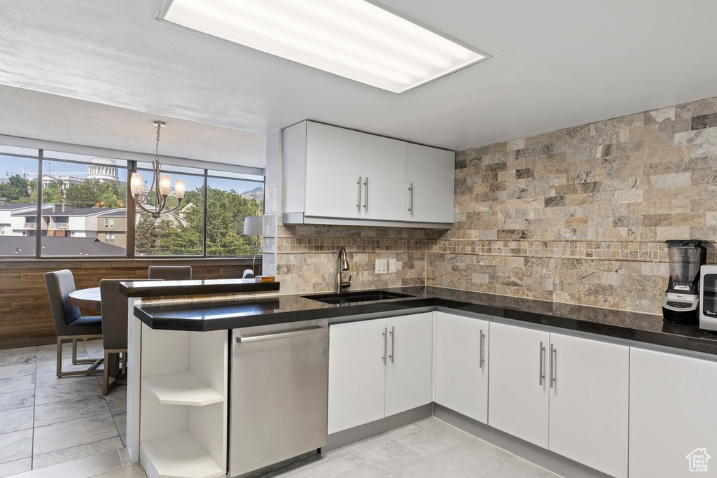 Kitchen featuring stainless steel dishwasher, white cabinets, backsplash, and dark countertops