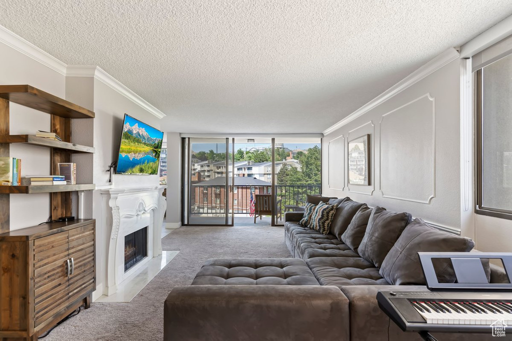 Carpeted living room with a textured ceiling, crown molding, a fireplace with flush hearth, and floor to ceiling windows