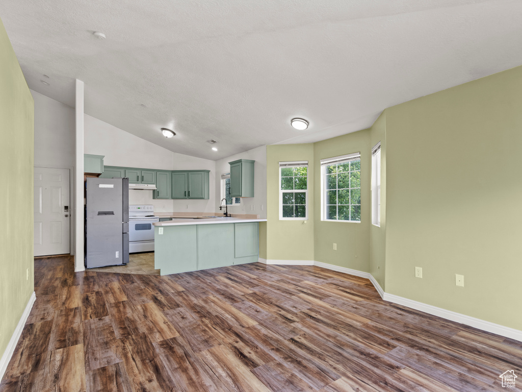 Kitchen with freestanding refrigerator, green cabinetry, white range with electric stovetop, a peninsula, and dark wood-style floors