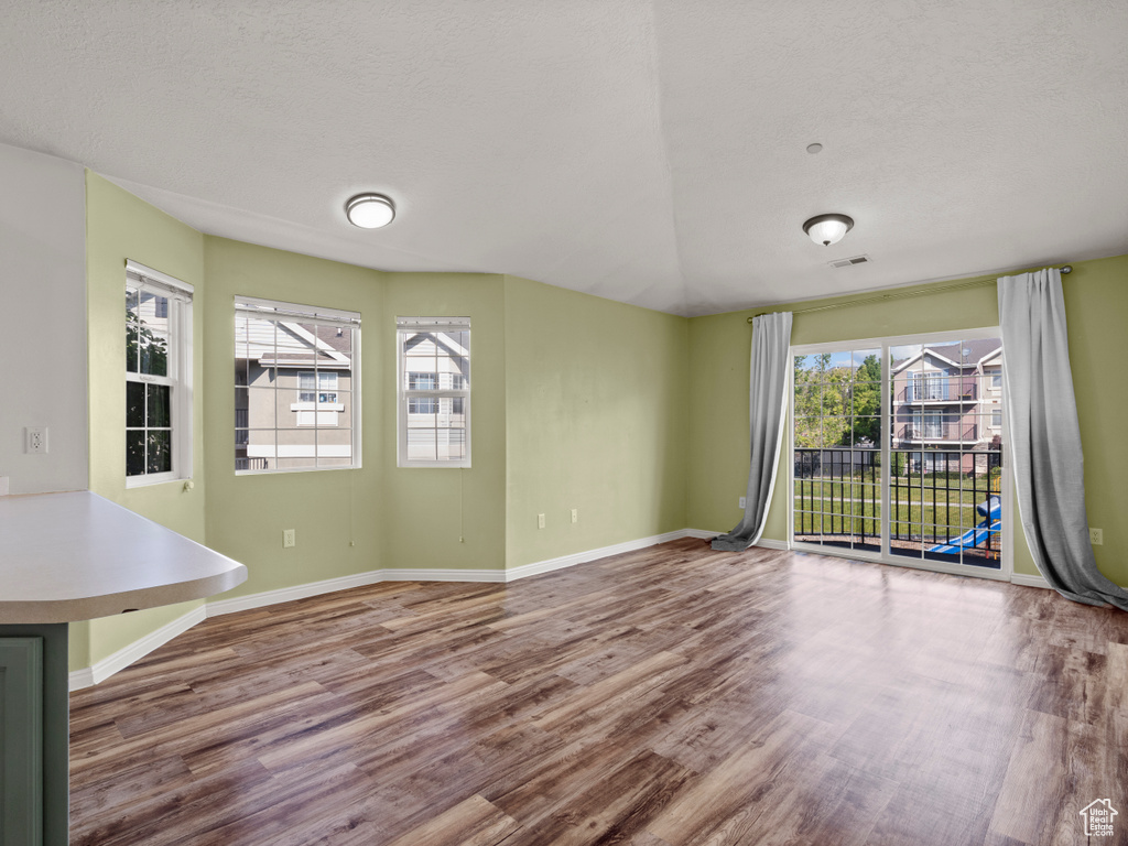 Unfurnished living room with wood finished floors, plenty of natural light, and a textured ceiling