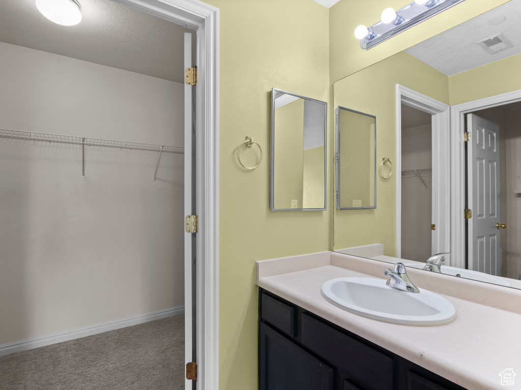 Bathroom with vanity and a walk in closet