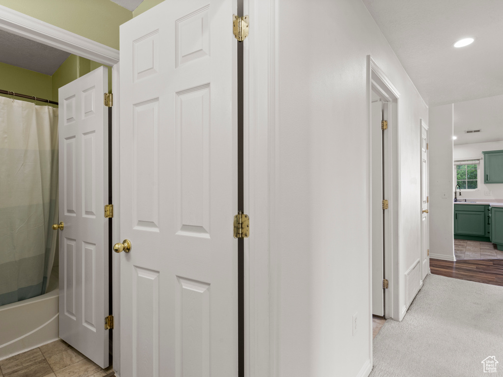 Corridor featuring recessed lighting and a sink
