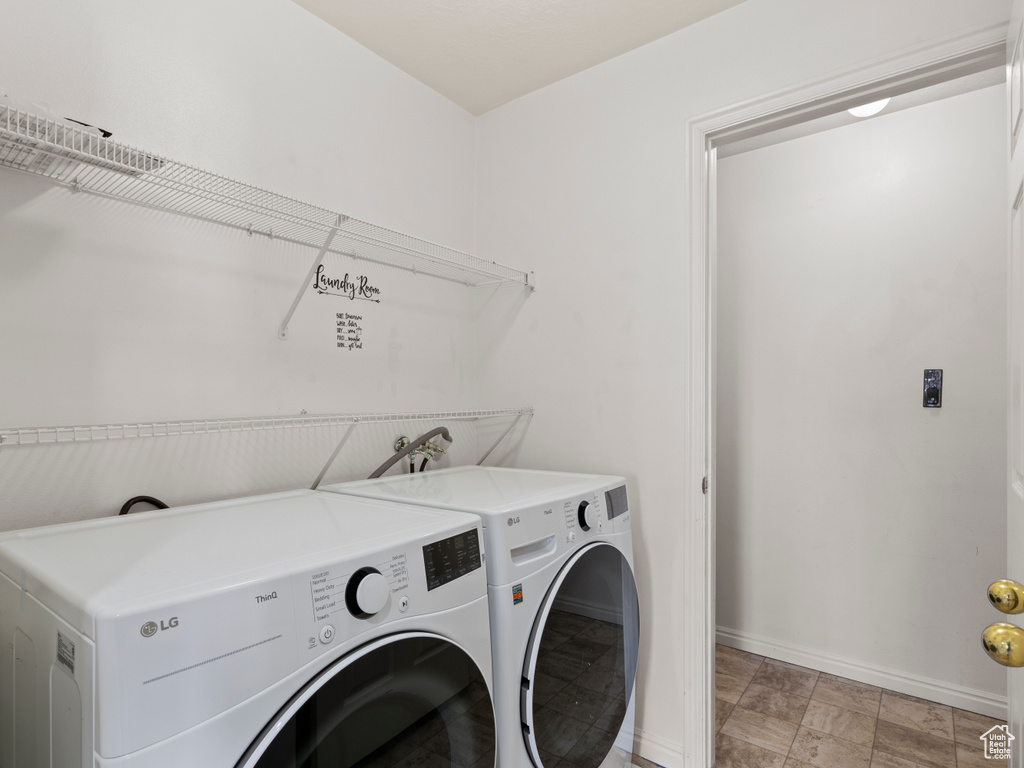Washroom featuring washing machine and clothes dryer and light stone finish flooring