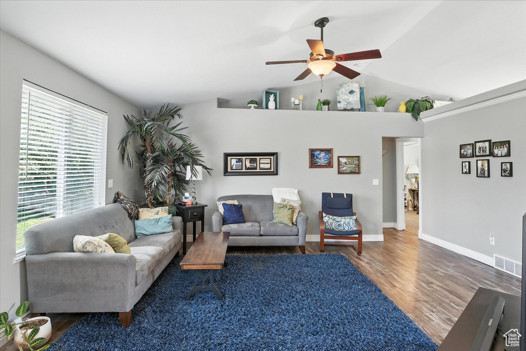 Living room with ceiling fan, wood finished floors, and high vaulted ceiling