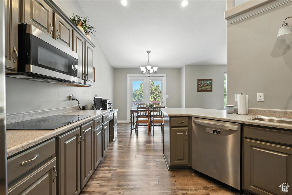 Kitchen featuring appliances with stainless steel finishes, a chandelier, light countertops, dark wood-style flooring, and decorative light fixtures