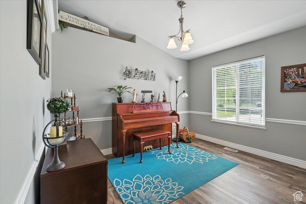 Living area with wood finished floors, a chandelier, and vaulted ceiling