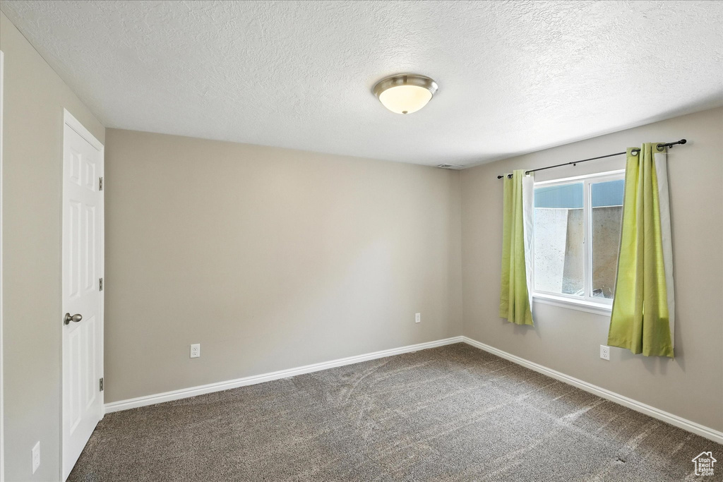 Carpeted empty room with a textured ceiling