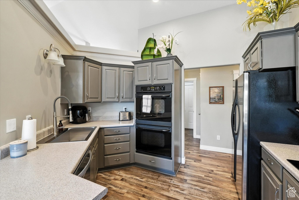 Kitchen with appliances with stainless steel finishes, gray cabinets, wood finished floors, and light countertops