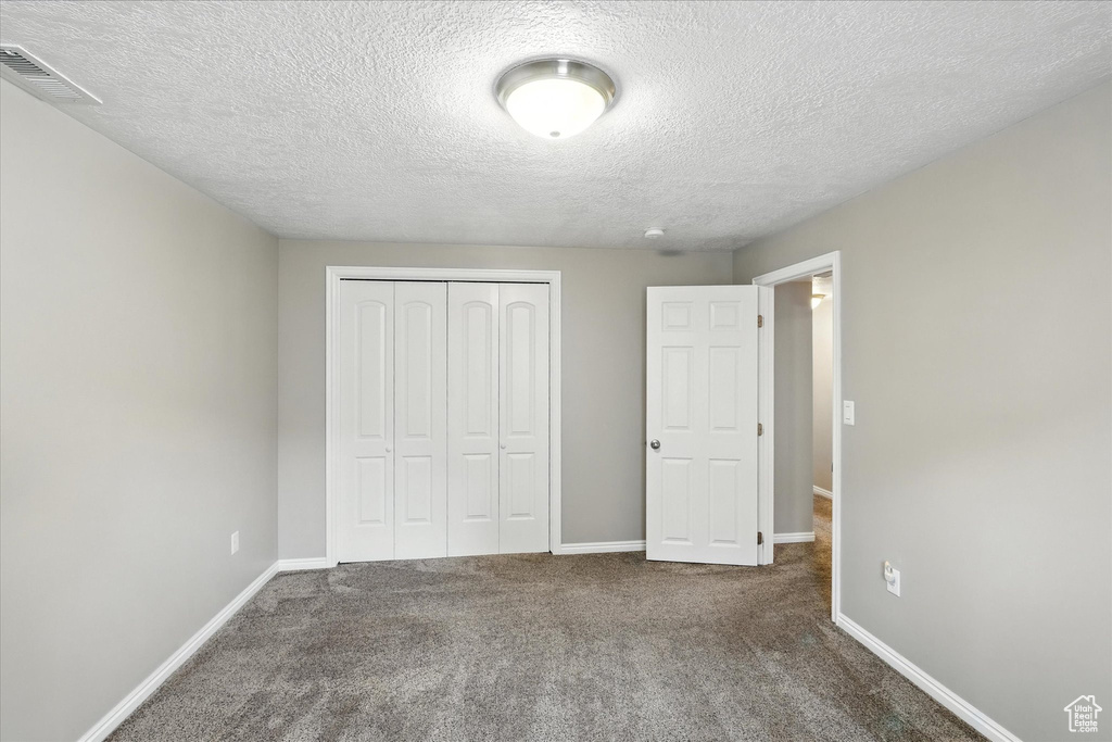 Unfurnished bedroom with carpet flooring, a closet, and a textured ceiling