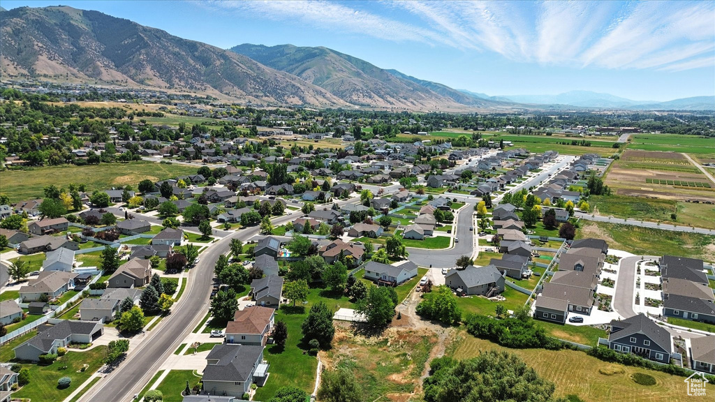 Aerial view of property and surrounding area featuring a mountainous background and nearby suburban area