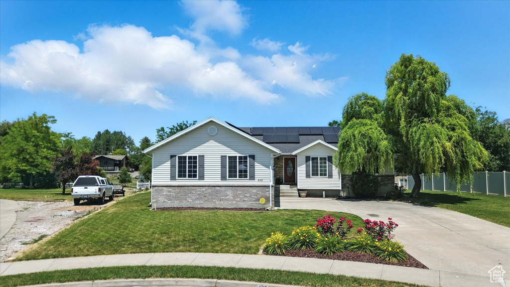 Ranch-style home featuring solar panels and driveway