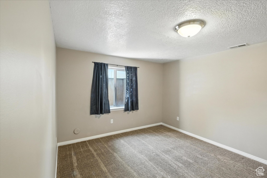 Carpeted empty room featuring a textured ceiling