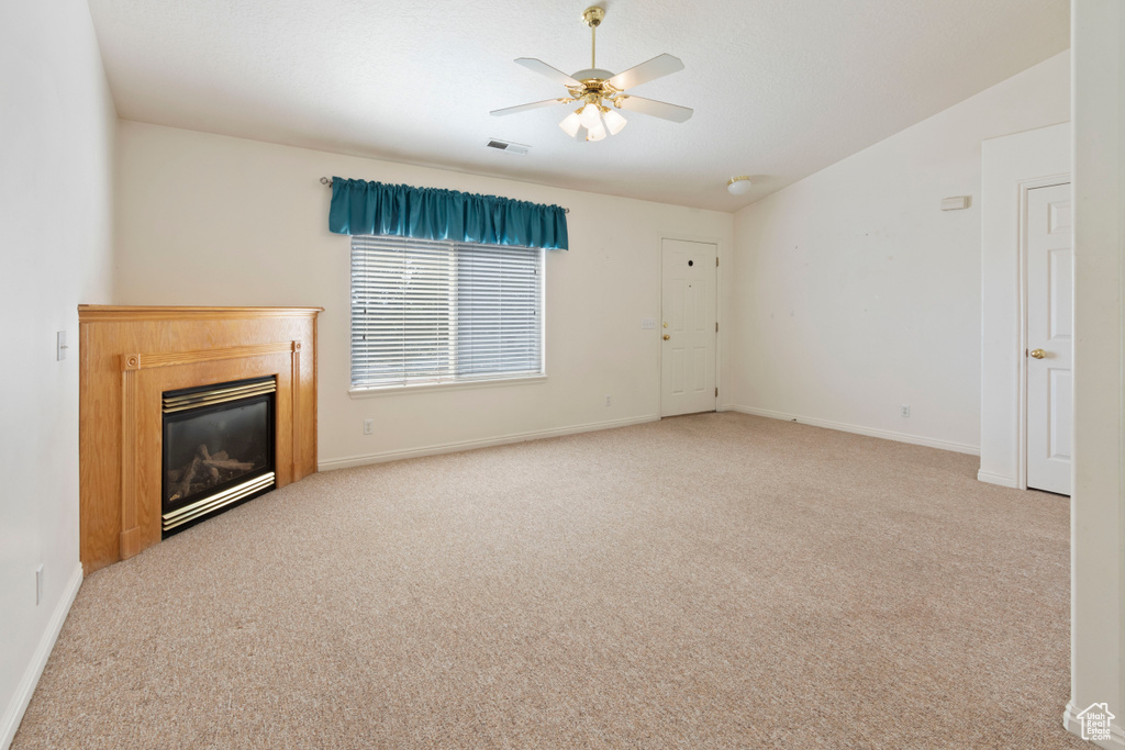 Unfurnished living room with a ceiling fan, a glass covered fireplace, and carpet