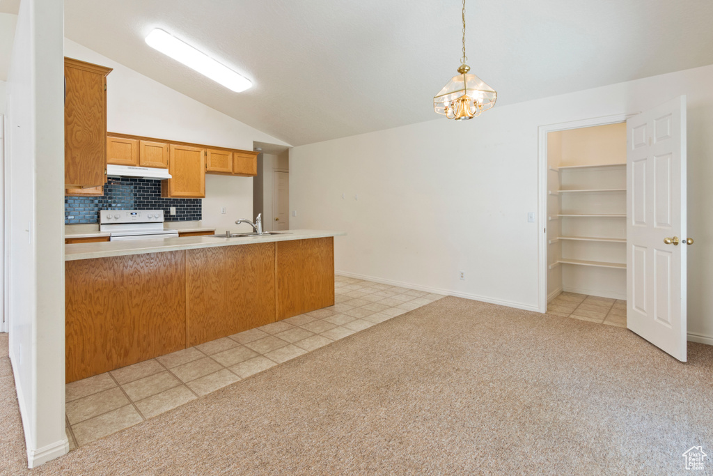 Kitchen featuring under cabinet range hood, white electric stove, lofted ceiling, light countertops, and decorative backsplash