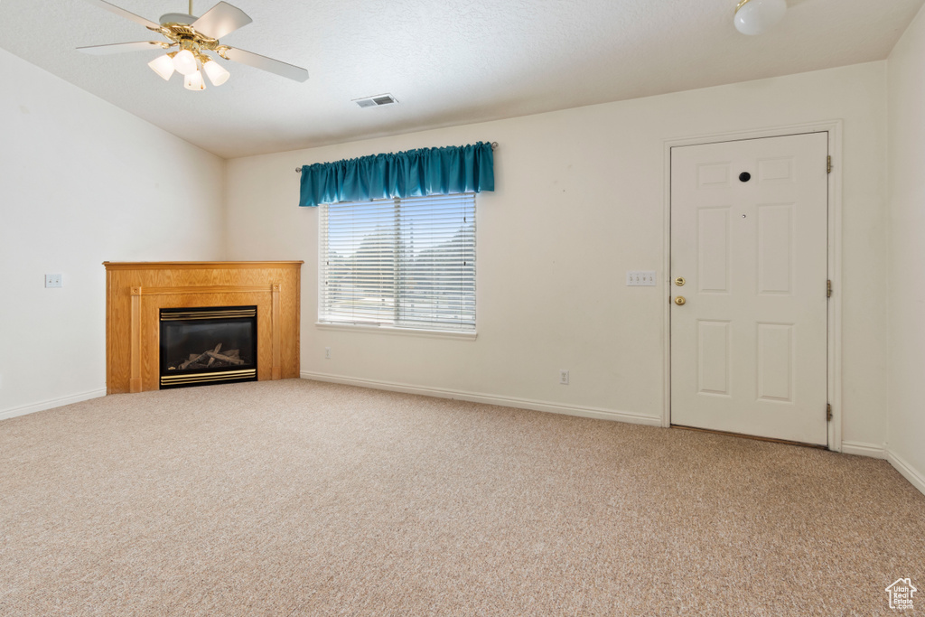 Unfurnished living room featuring carpet floors, a ceiling fan, and a glass covered fireplace