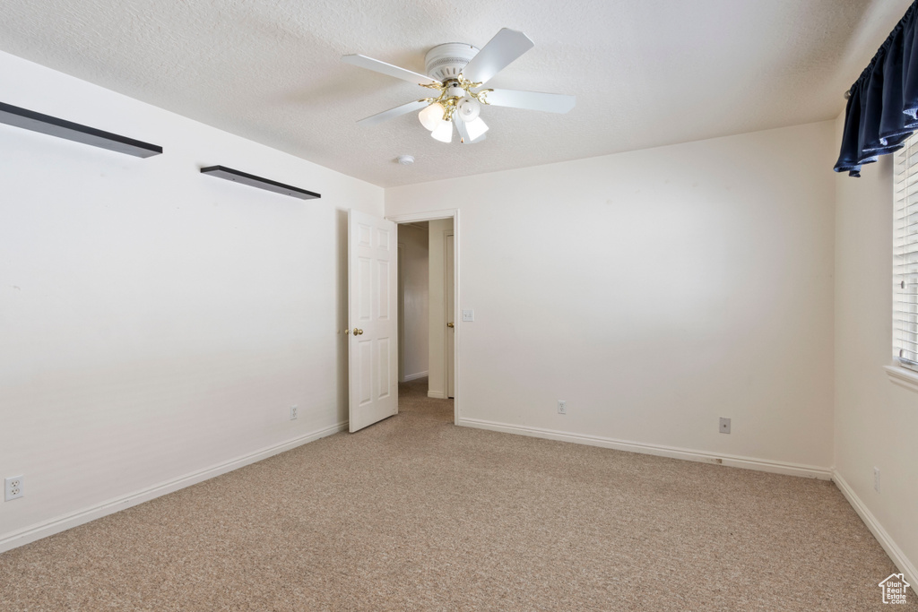 Empty room featuring light carpet and a ceiling fan