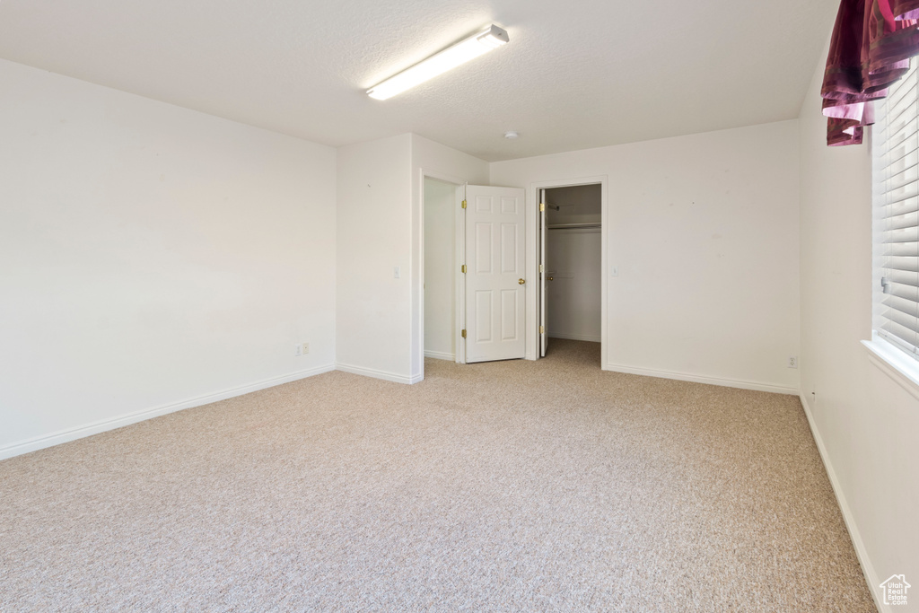 Unfurnished bedroom with light carpet, a closet, and multiple windows
