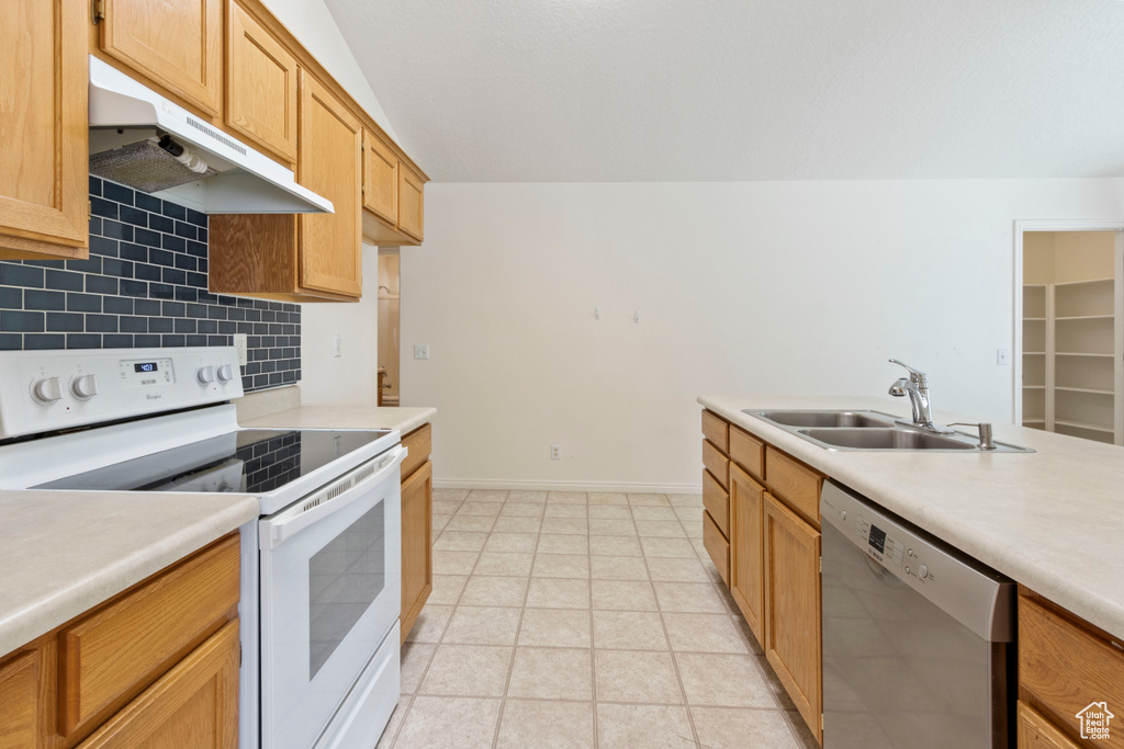 Kitchen with electric stove, dishwasher, under cabinet range hood, light countertops, and tasteful backsplash