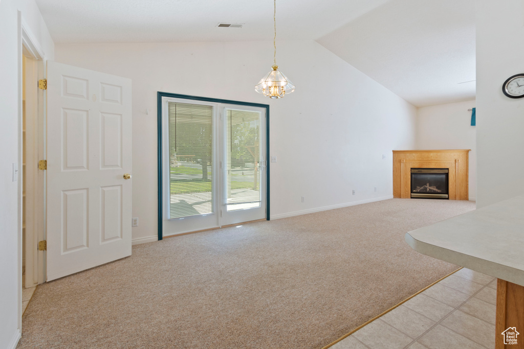 Unfurnished living room with vaulted ceiling, light colored carpet, a chandelier, and a glass covered fireplace