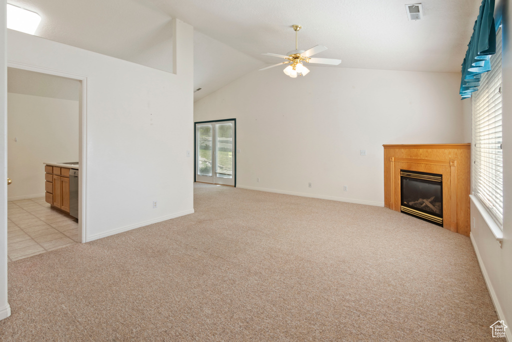 Unfurnished living room with light colored carpet, ceiling fan, lofted ceiling, and a glass covered fireplace