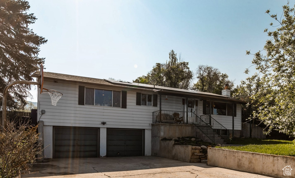 Single story home with a garage, concrete driveway, a porch, and a chimney