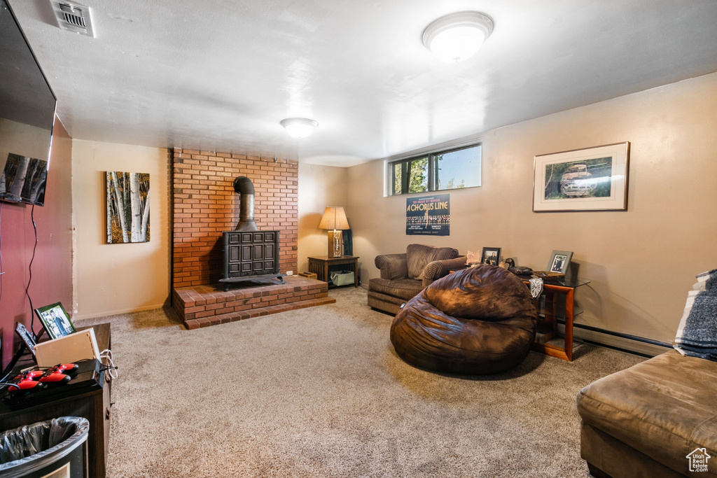 Carpeted living area featuring a wood stove and a baseboard radiator